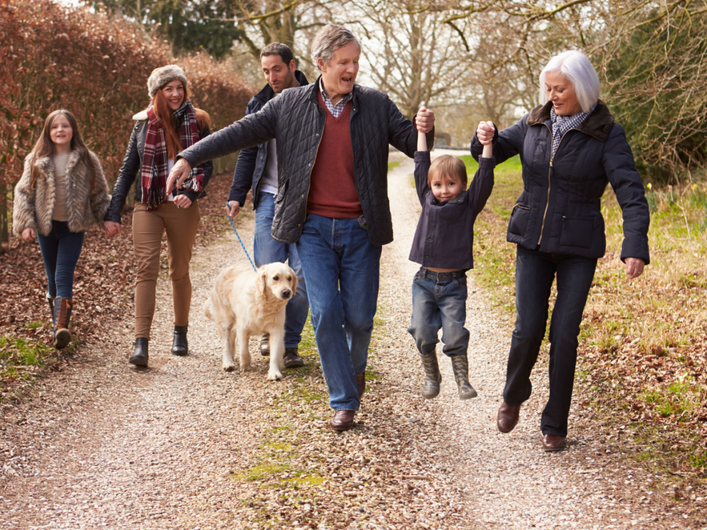 An extended family group take an autumnal woodland walk with their golden retriever. They are well supported in a family programme.