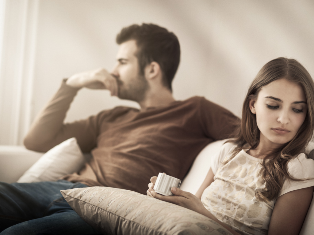 a couple sit looking away from each other in conflict. They demonstrate that one might need addiction therapy for a co-dependent relationship.